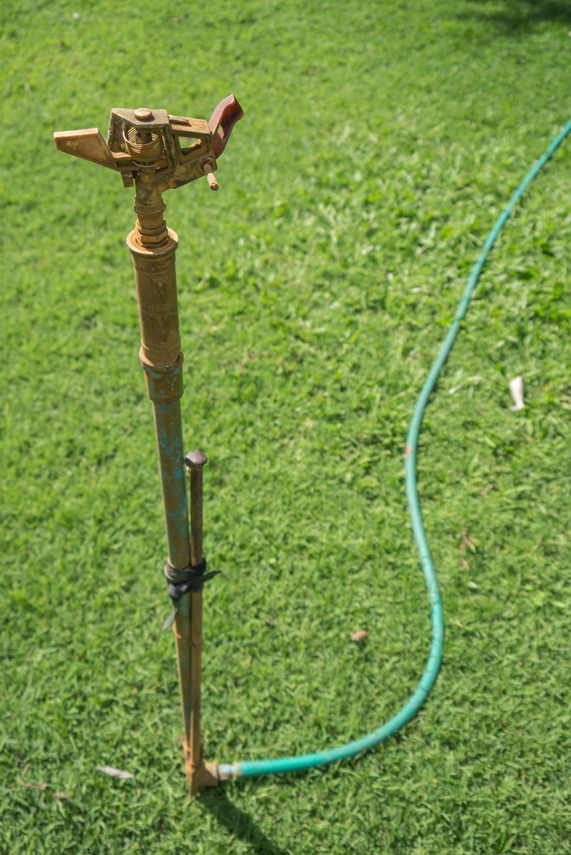 An outdated metal sprinkler on top of the grass