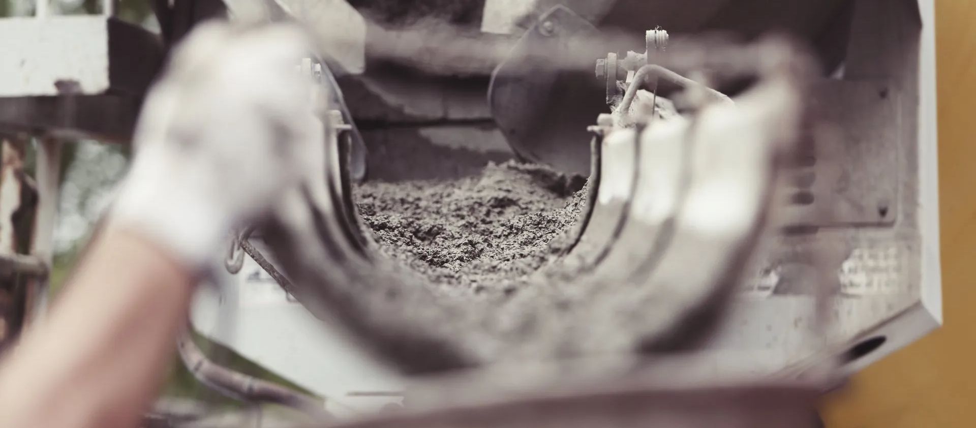 Hands of concrete workers working with molds and shoveling wet cement