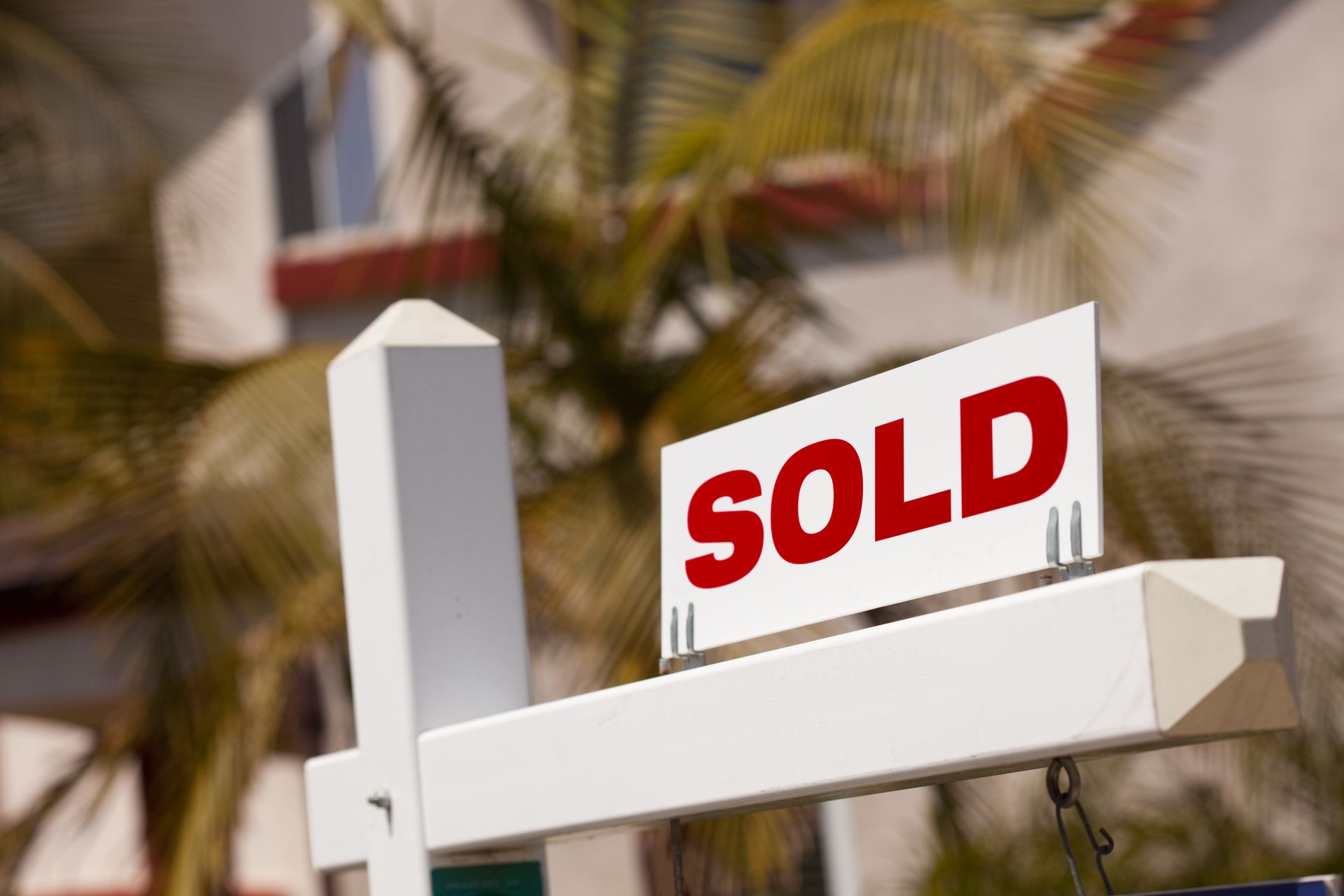 A sold sign is hanging from a pole in front of a building.