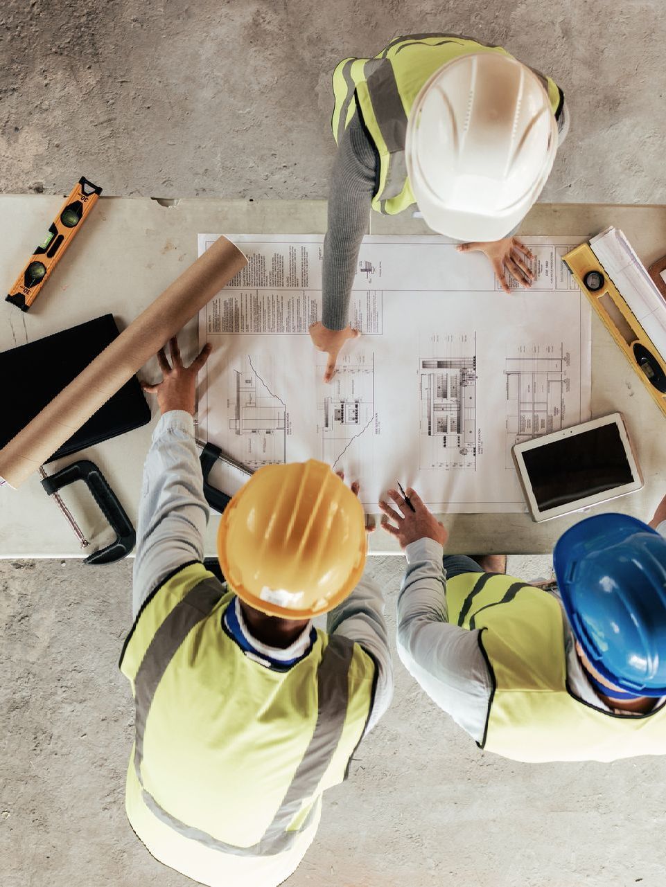 A group of construction workers are sitting around a table looking at a blueprint.