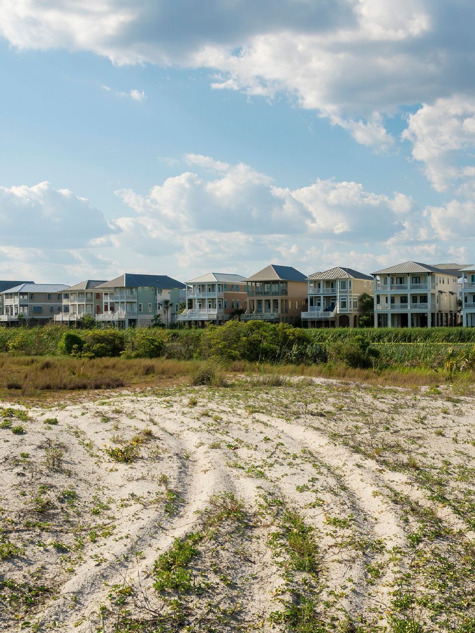 A row of houses sitting on top of a sandy field.