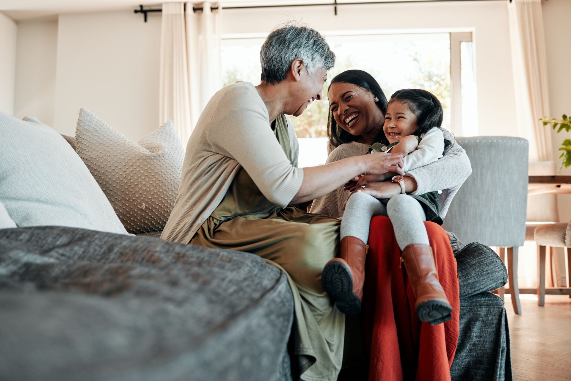 A group of women are sitting on a couch hugging a little girl.
