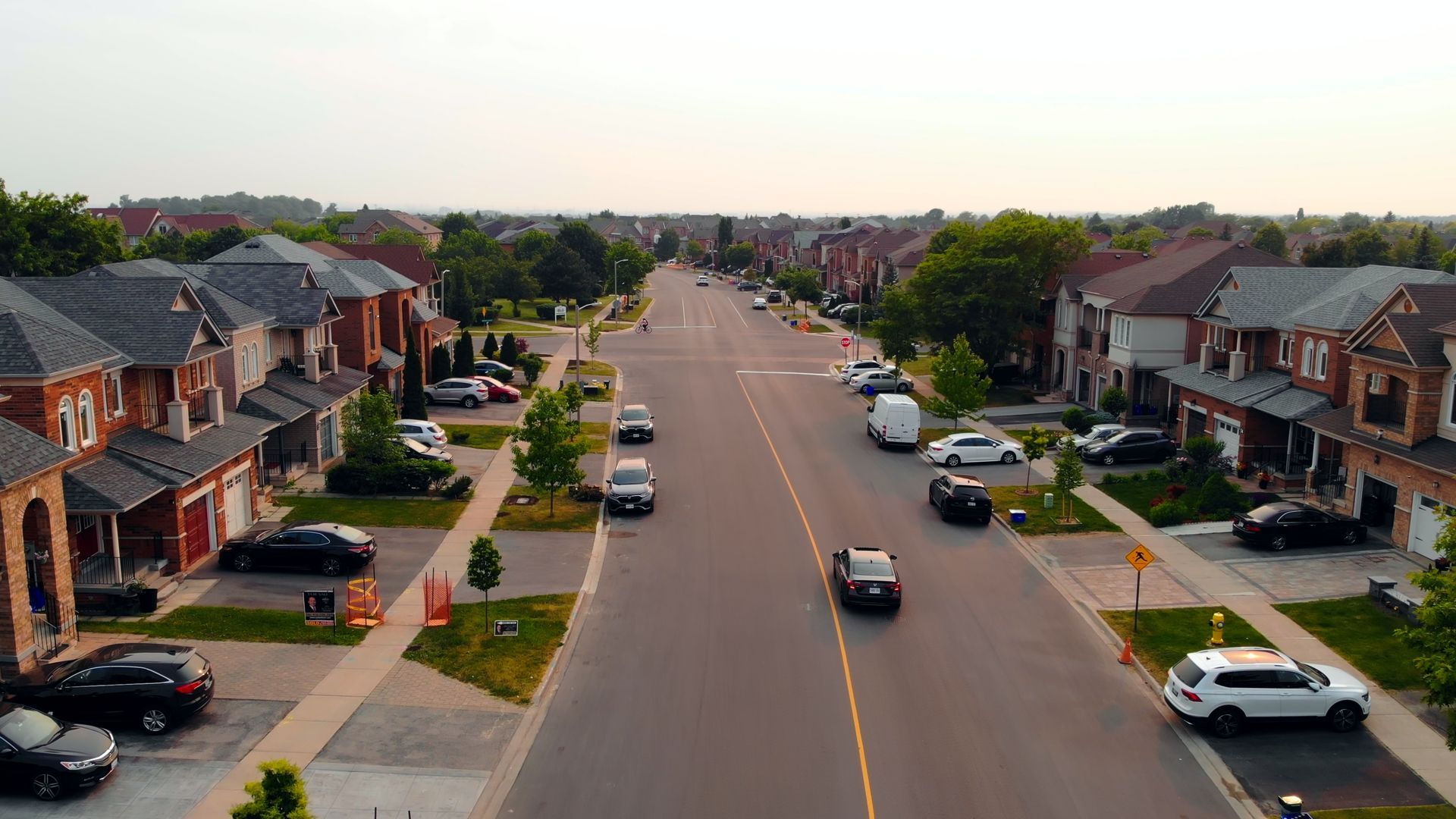 An aerial view of a residential street with cars driving down it.