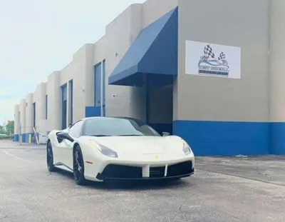 A white sports car is parked in front of a building.
