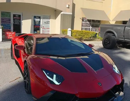 A red lamborghini aventador is parked in front of a building.
