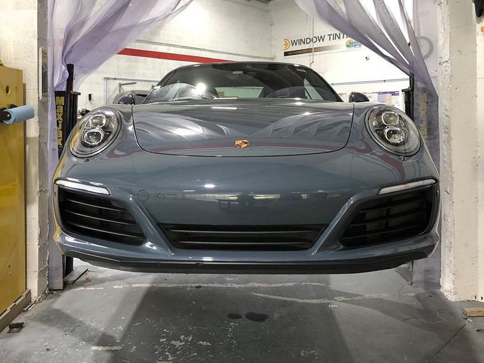 A porsche 911 is sitting on a lift in a garage.