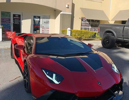 A red lamborghini aventador is parked in front of a building.