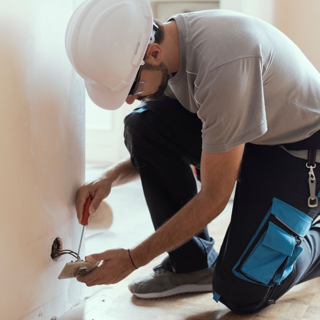 electrician installing new wires in the house wall