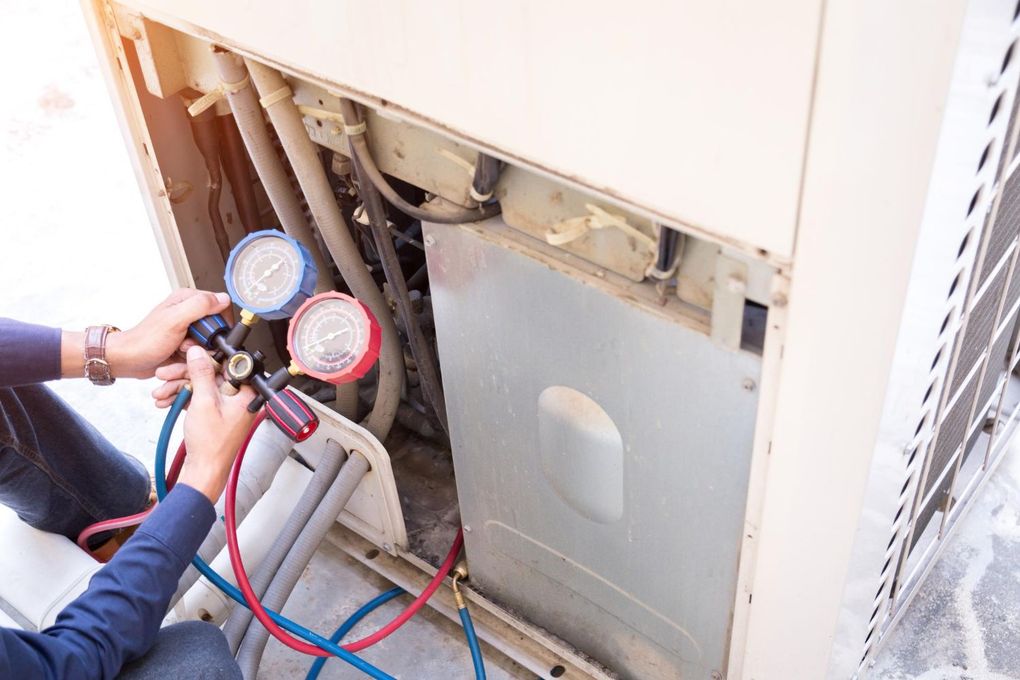Person using gauges to service an air conditioning unit.