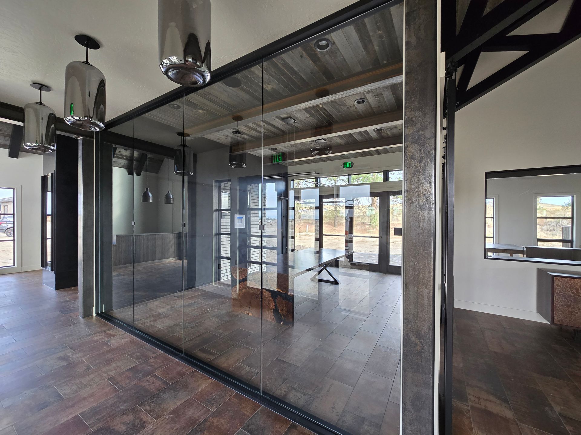 Modern interior with large glass-walled conference room, wood-plank ceiling, metal beams, and industrial-style lighting.