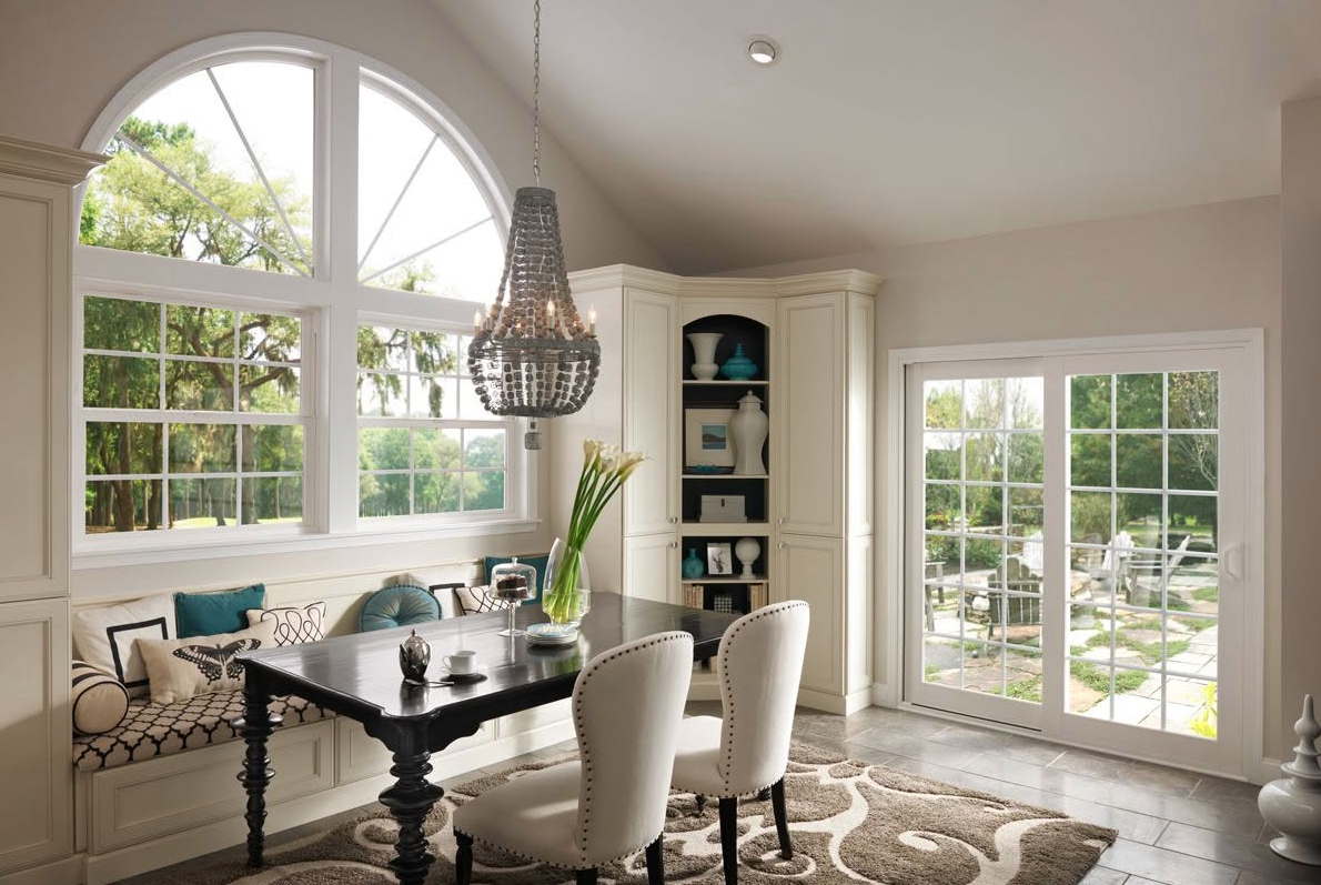 Bright dining room with arched window, black table, cream chairs, and French doors to a garden