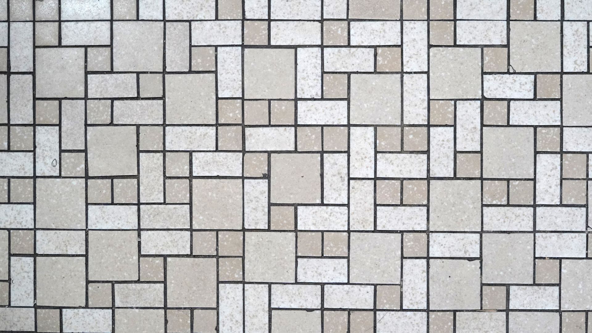 Beige and white tiled wall with a geometric pattern of various-sized squares and rectangles.