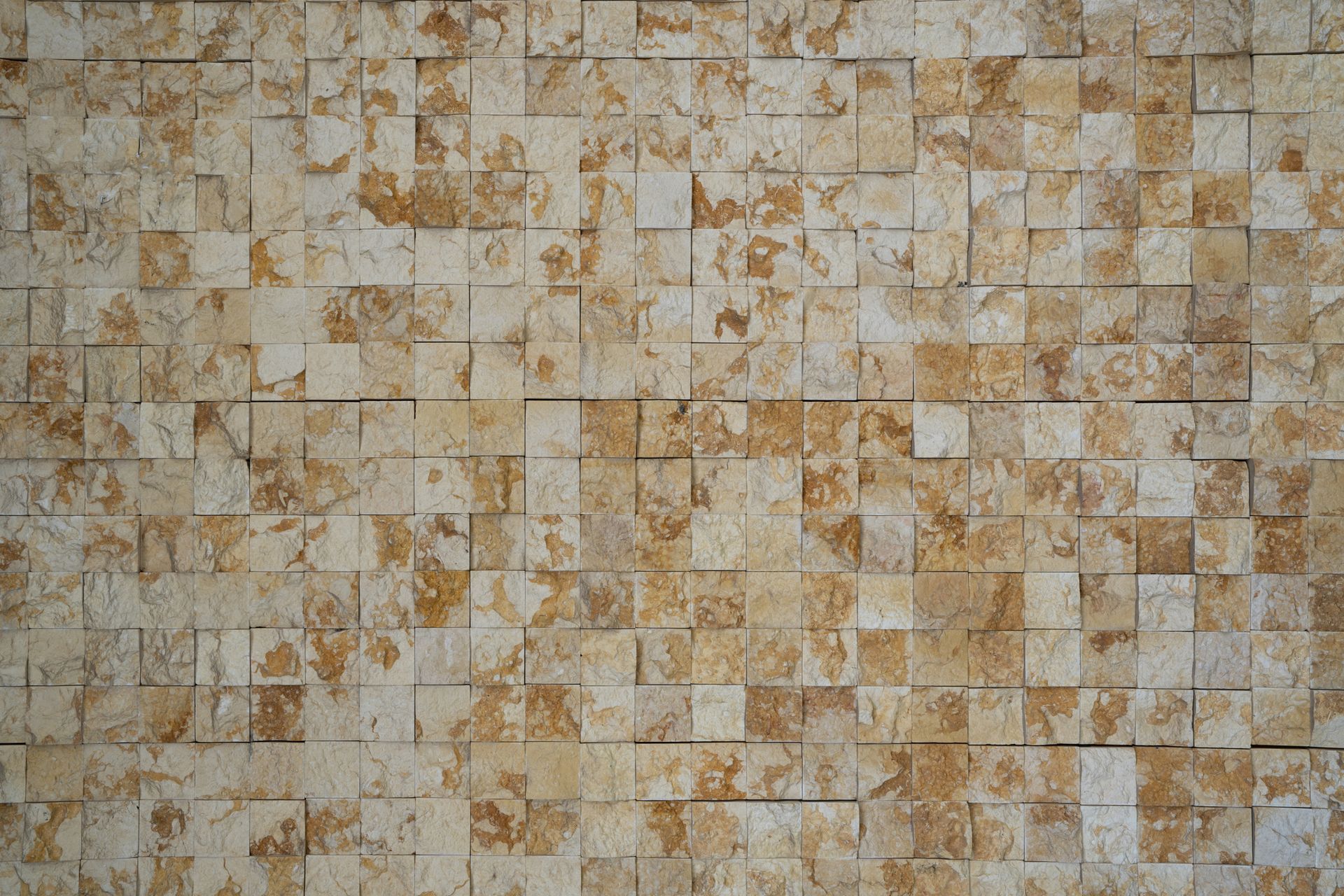 Textured wall of beige and brown square tiles.