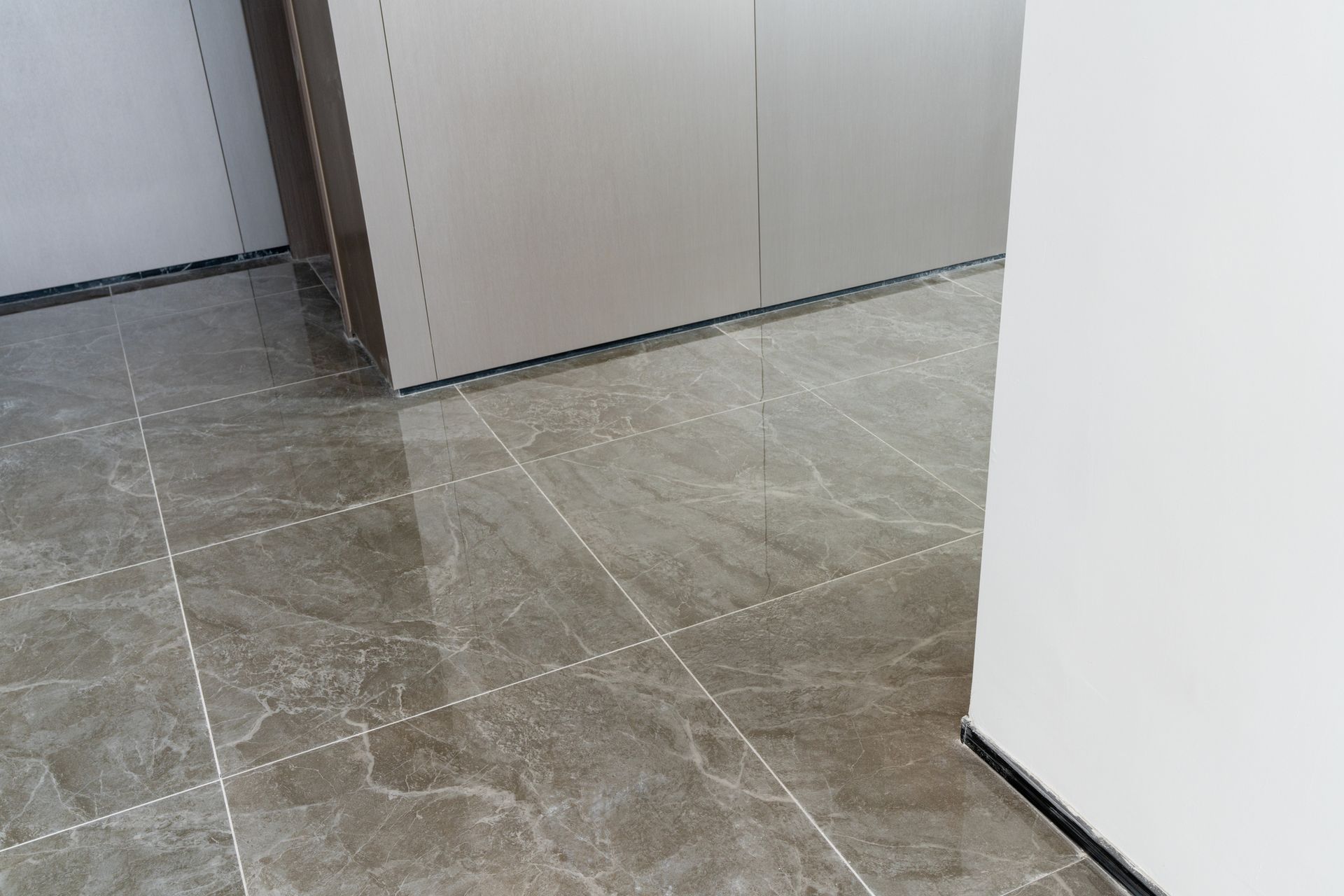 Gray marbled tile floor, a cabinet and white wall.