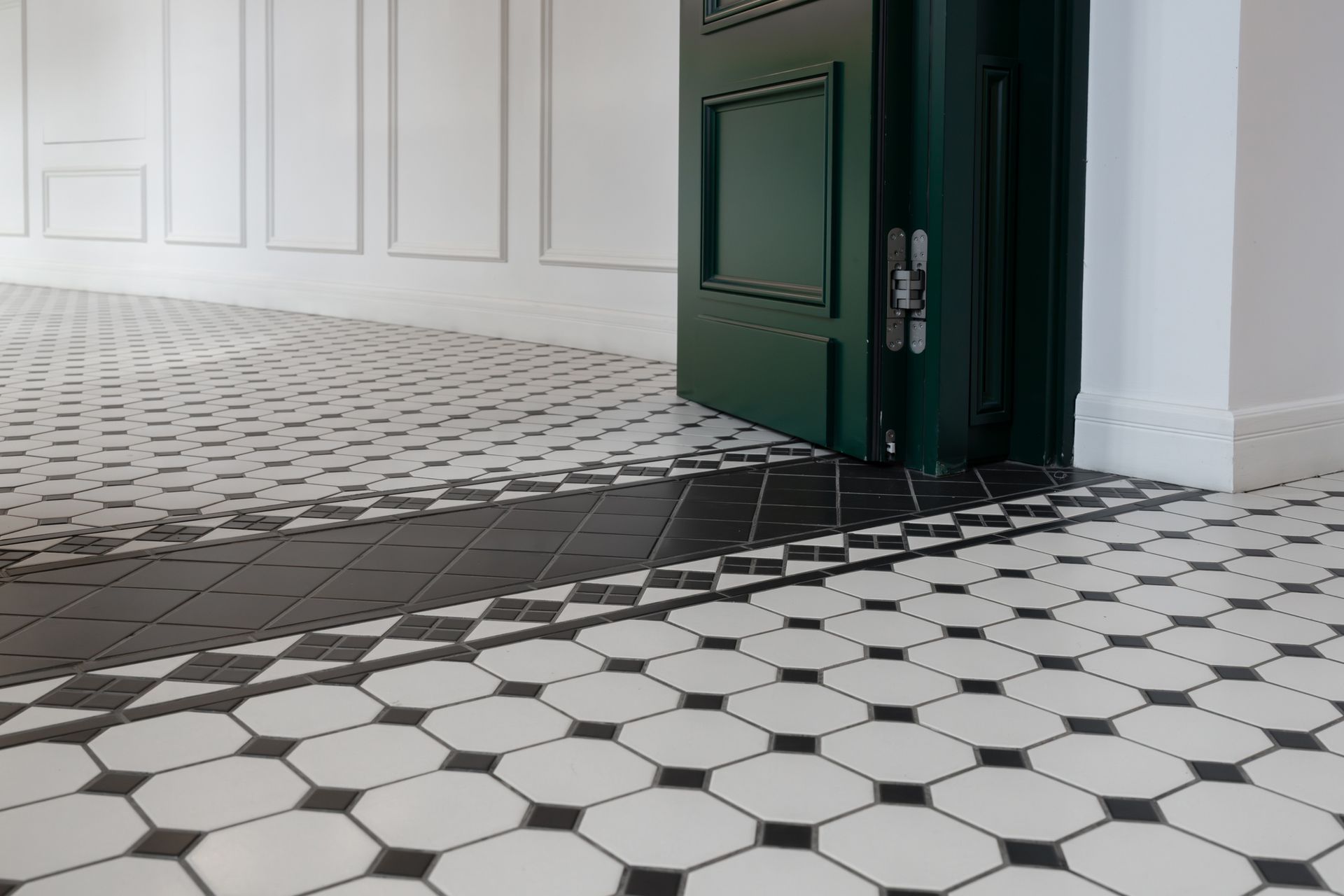 Black and white tiled floor with a black border, green door, and white walls. Black and white tiled floor with a black border, green door, and white walls.