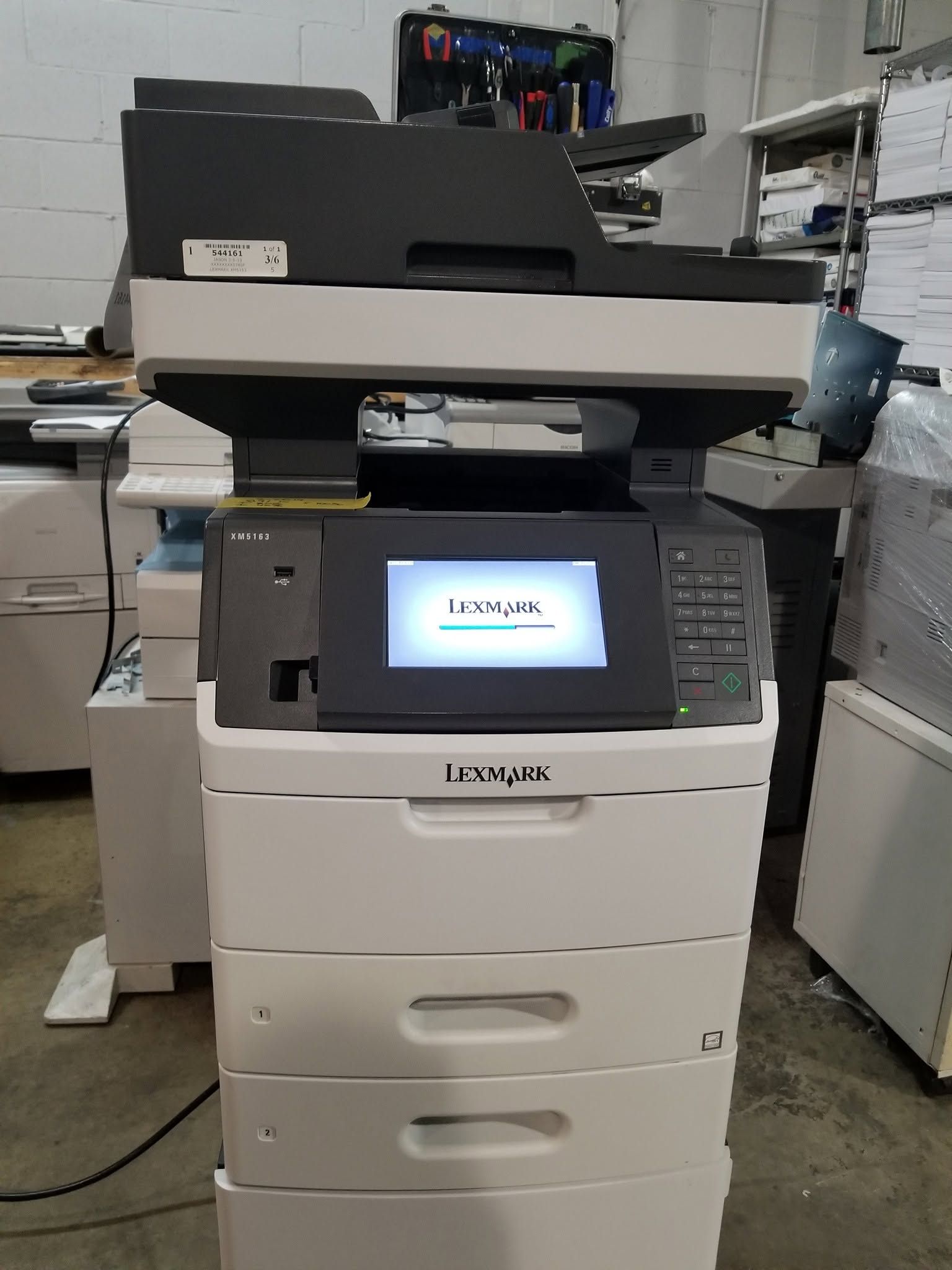 Large white and black office copier with touchscreen display in a print room