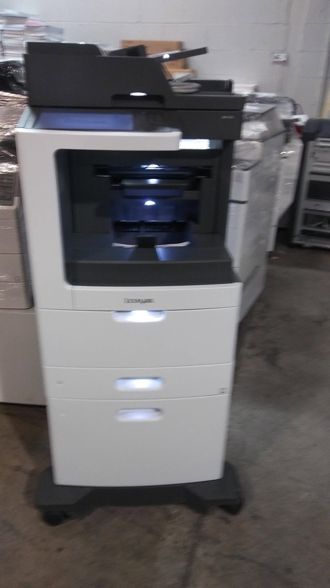 White office printer/copier on a wheeled base in a storage or office area