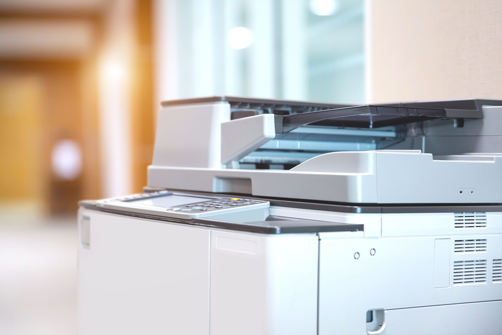 Modern office copier with paper tray in a bright workspace