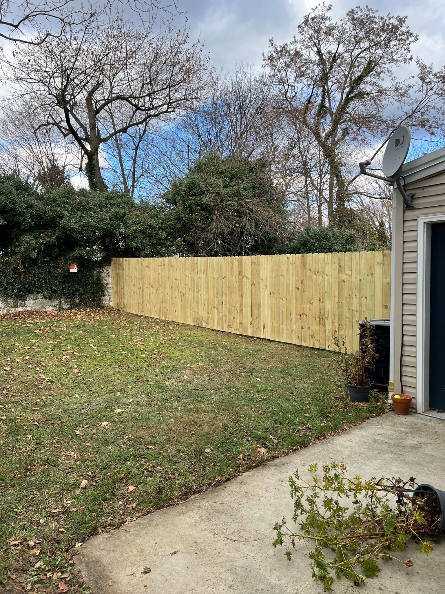 A wooden fence is in the backyard of a house.