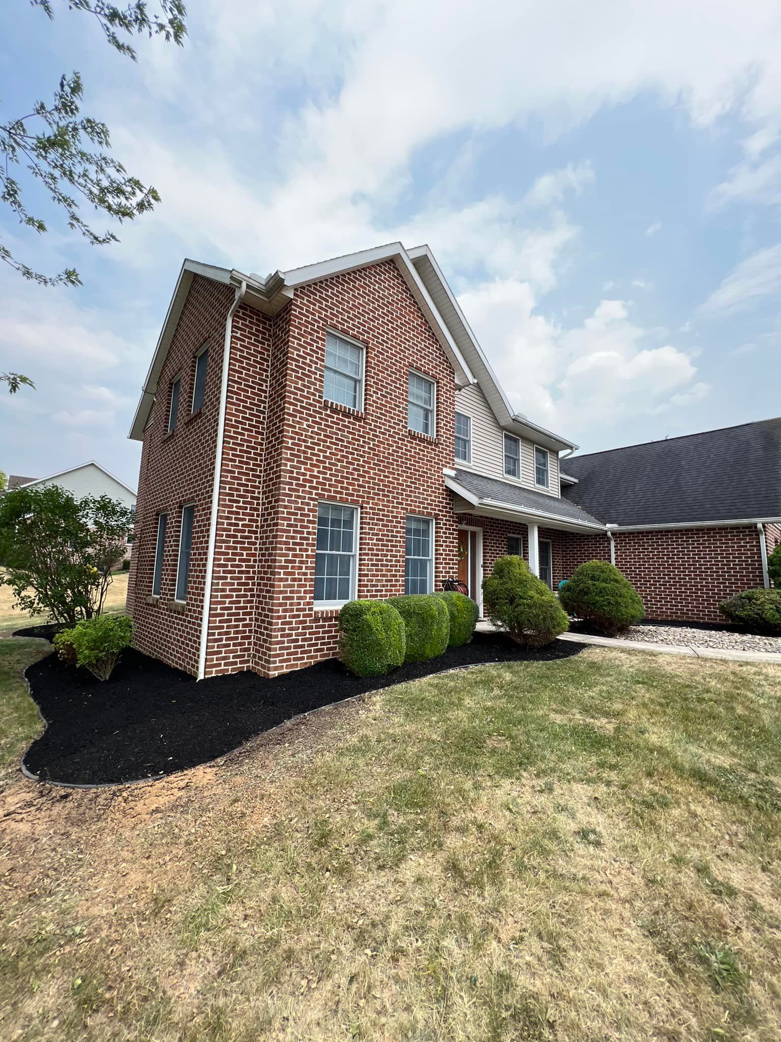 A large brick house with a large lawn in front of it.
