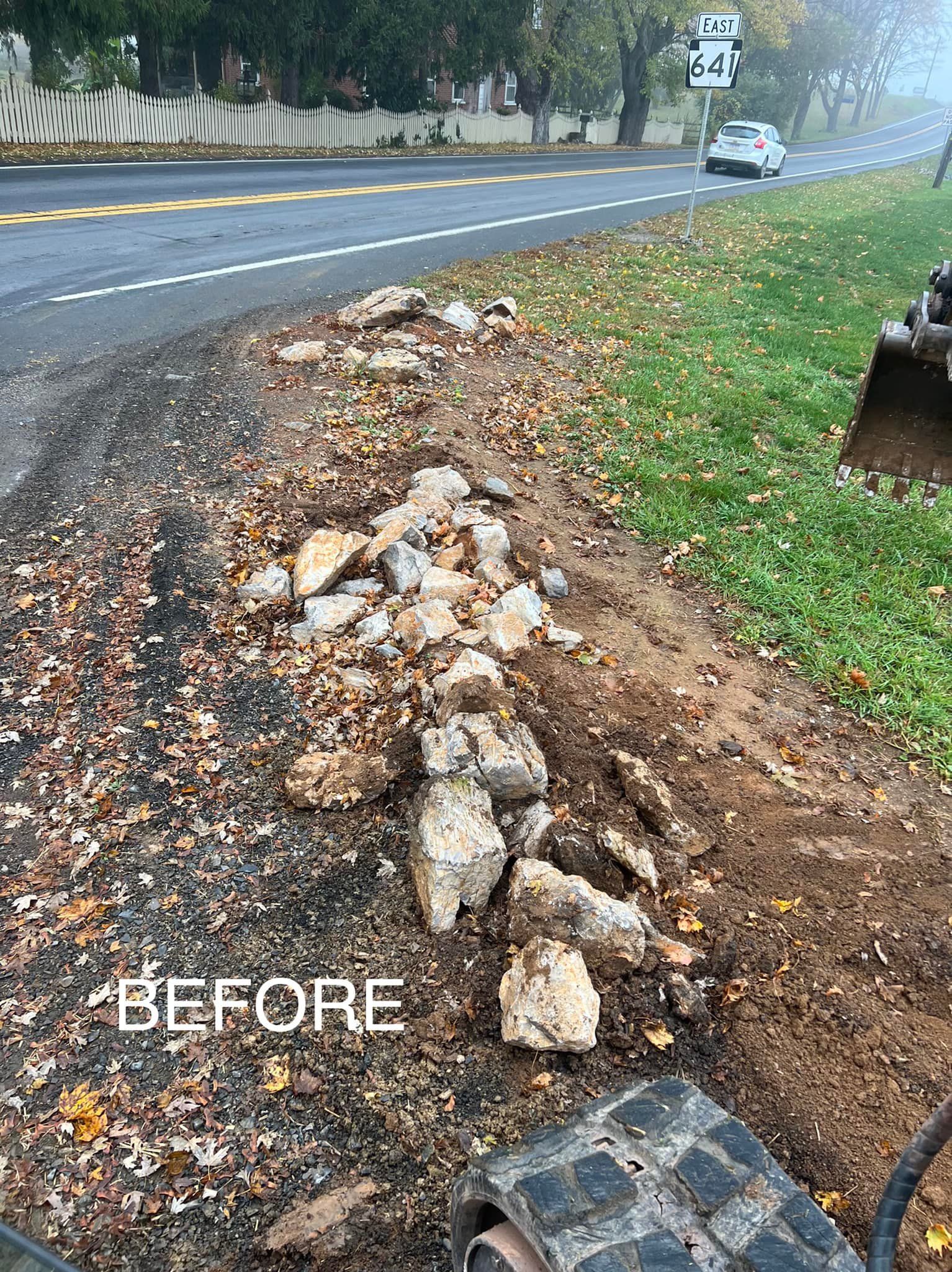 A pile of rocks is sitting on the side of a road next to a road.