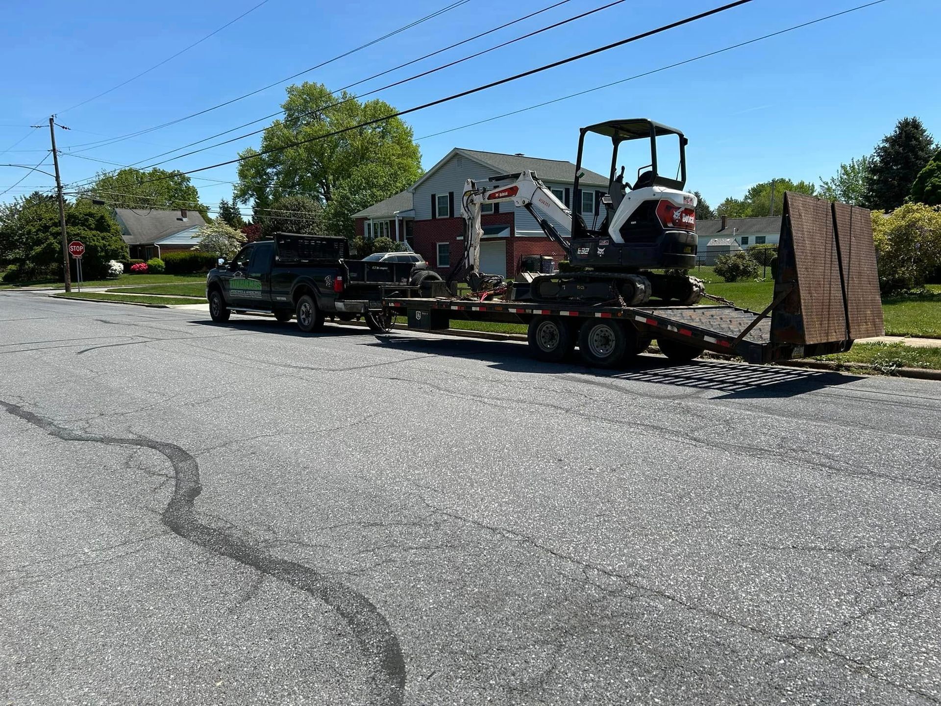 A jeep is towing a small excavator on a trailer