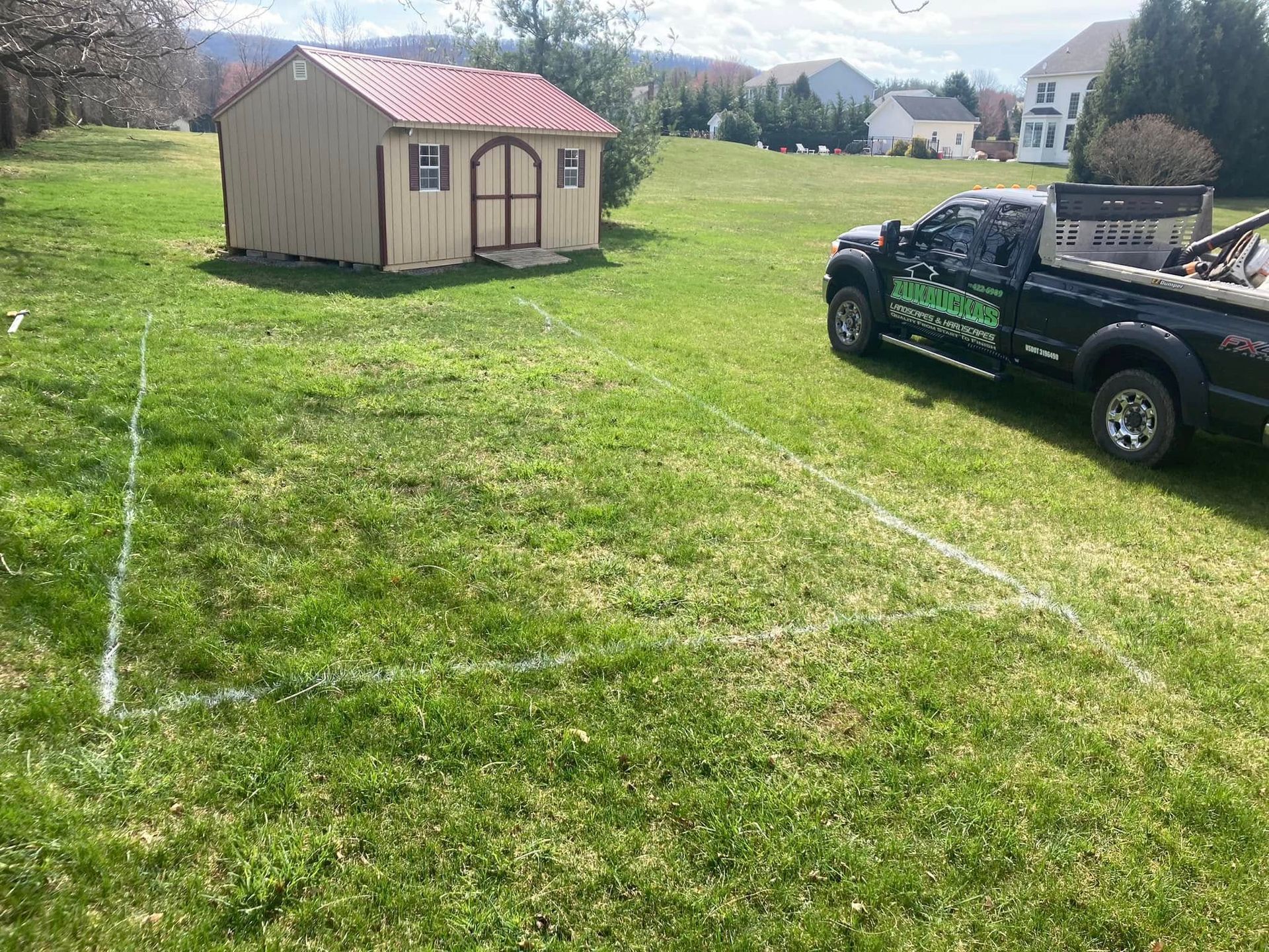 A truck is parked in a grassy field next to a shed.