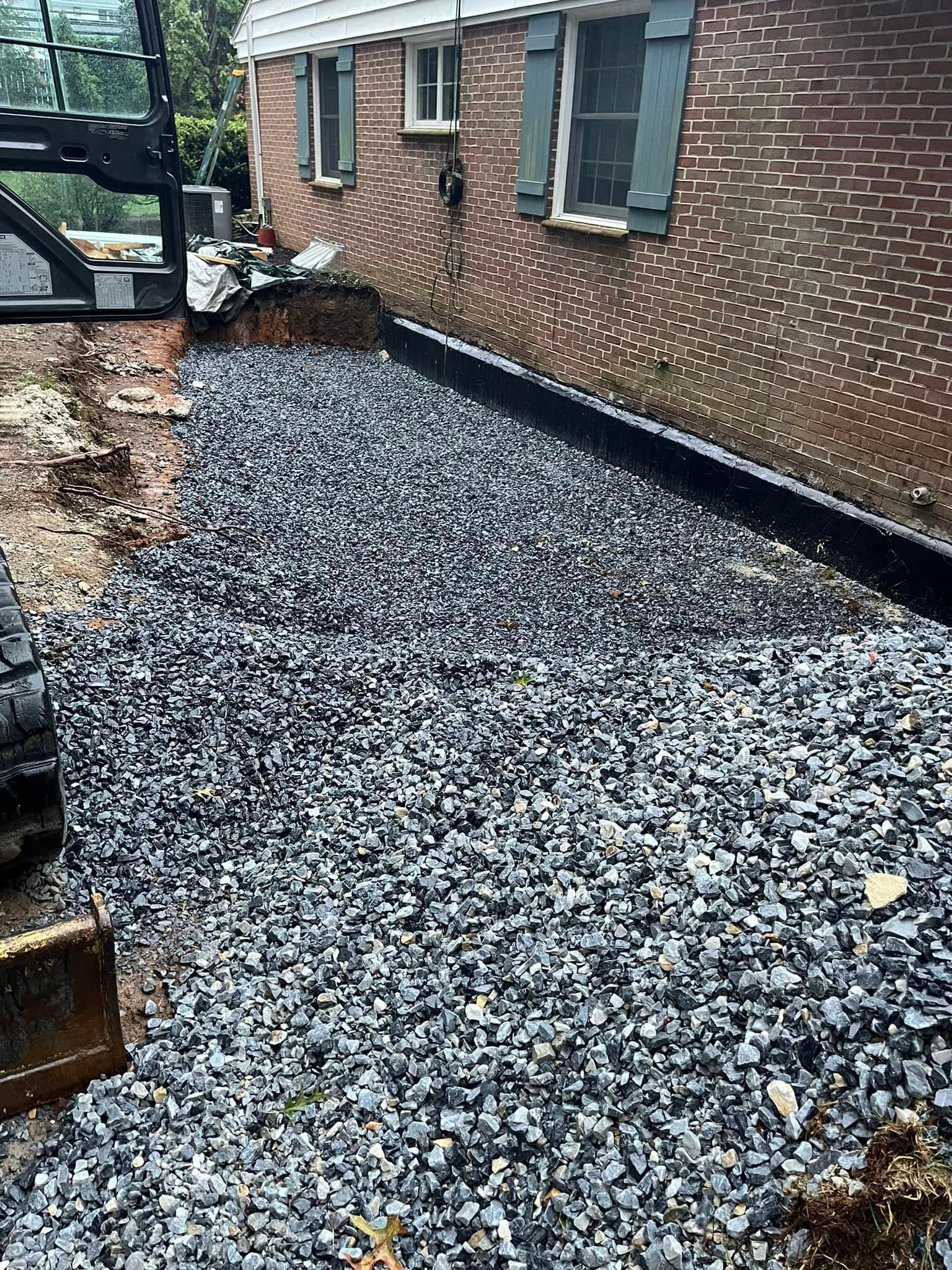 A pile of gravel is sitting in front of a brick house.