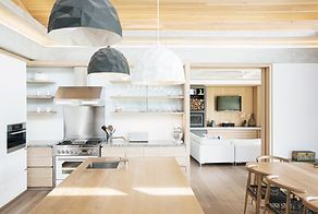 A kitchen with a large island , a stove , a table and chairs.