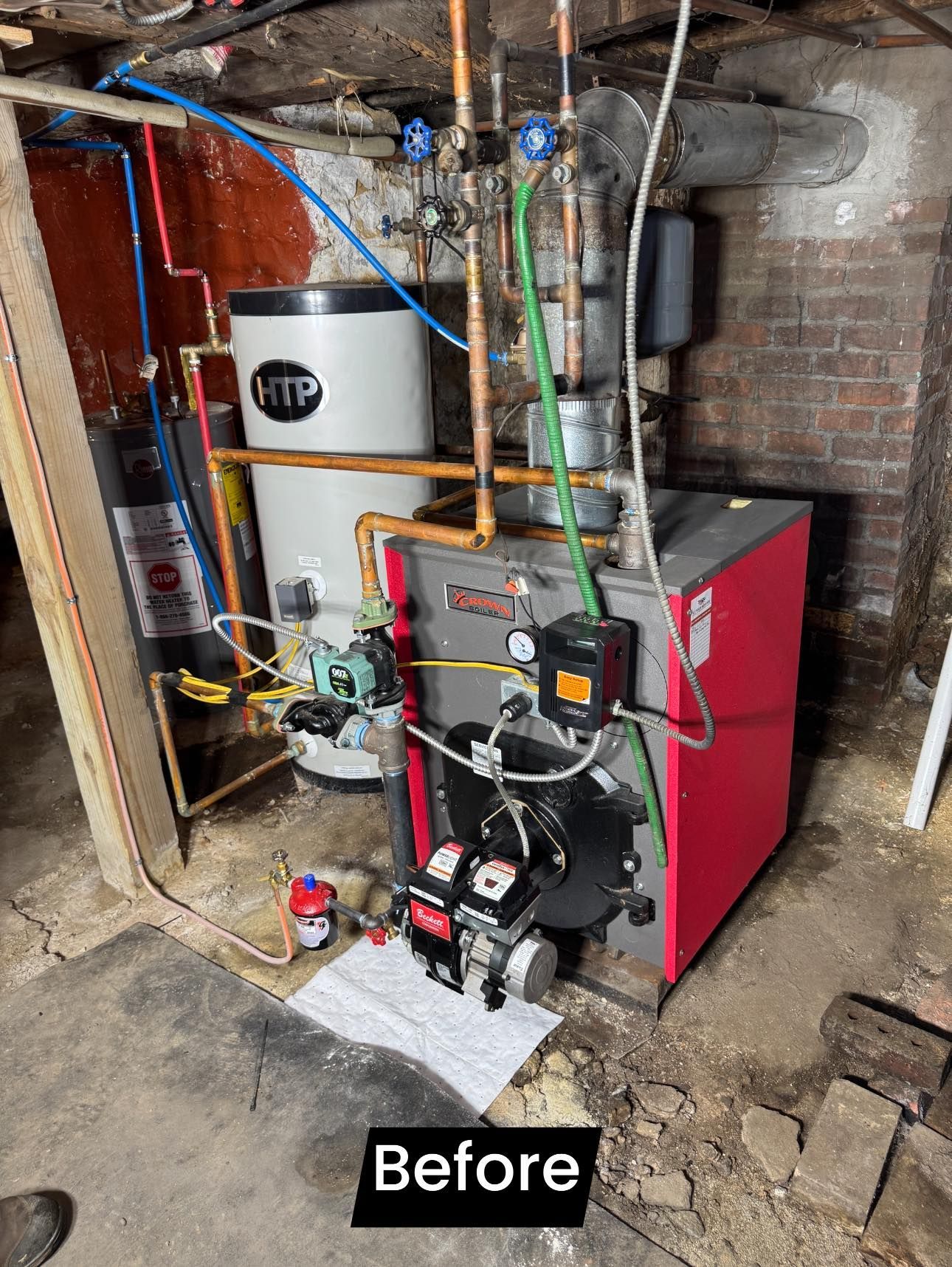 Basement boiler and water heater setup with exposed pipes and red heating unit, labeled “Before”
