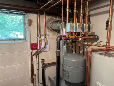 Basement utility room with water heater, pressure tank, and copper plumbing pipes