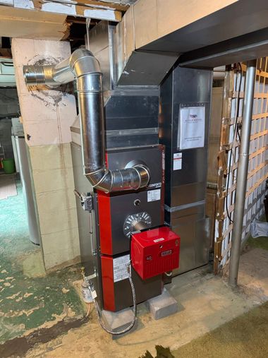 Red boiler and silver vent pipe in a basement utility area