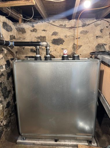 Large metal tank with pipes and gauge in a basement utility room