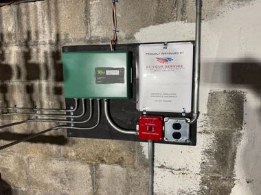Two electrical control boxes mounted on a concrete wall with conduit and a red switch box.