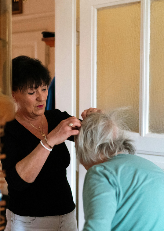 A woman in a black shirt is brushing another woman 's hair