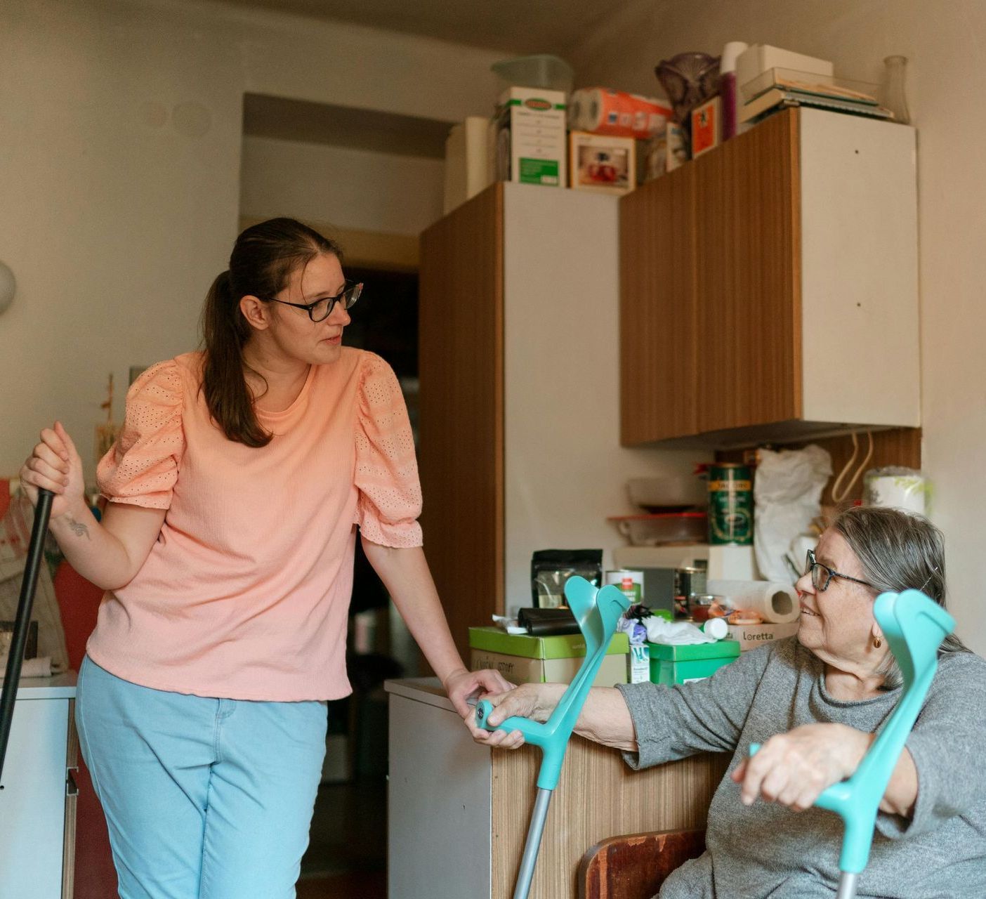 A woman is standing next to an older woman with crutches.