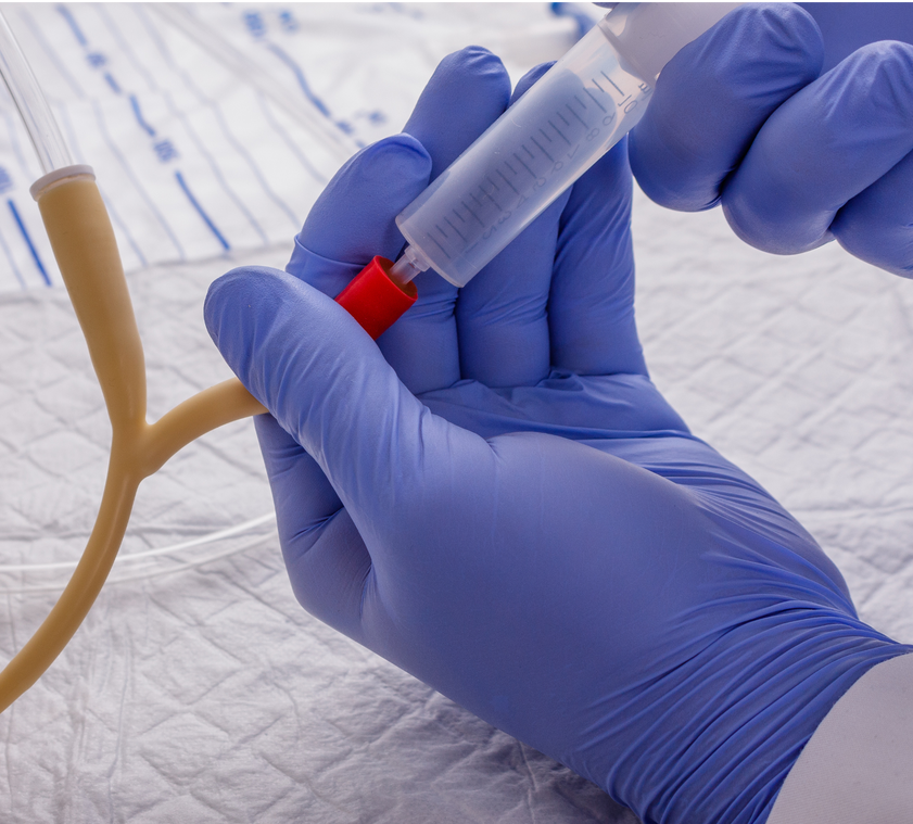 A person wearing blue gloves is holding a syringe