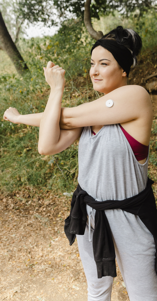 A woman with a patch on her arm is stretching her arms.