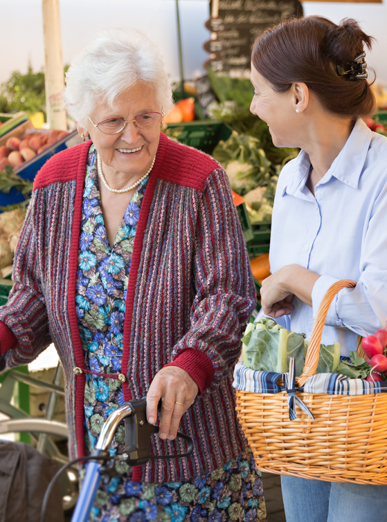 A woman is helping an elderly woman with her walker