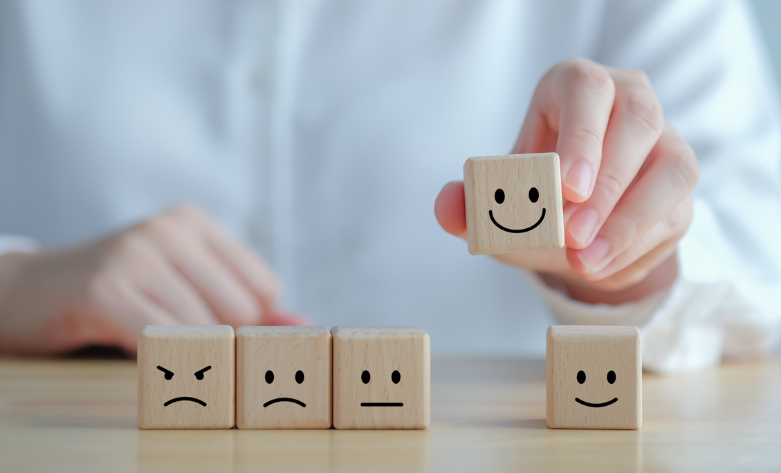A person is holding a wooden block with a smiley face on it.