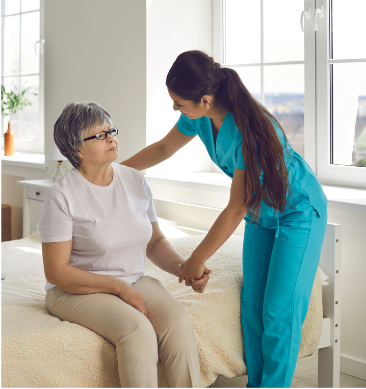 A nurse is helping an elderly woman sit on a bed.