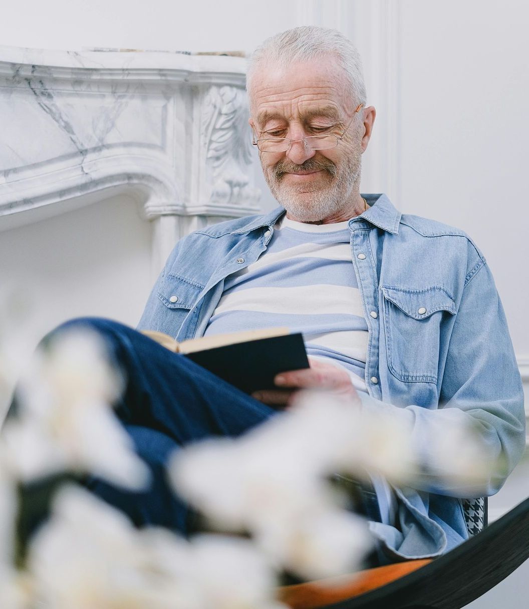 A man is sitting in a hammock reading a book.
