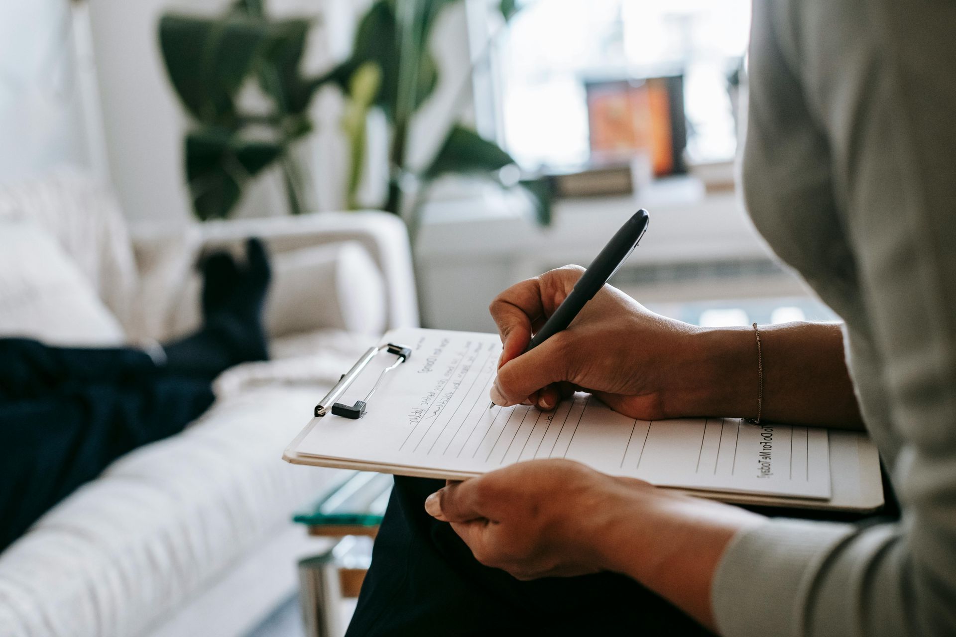A person is writing on a clipboard with a pen.