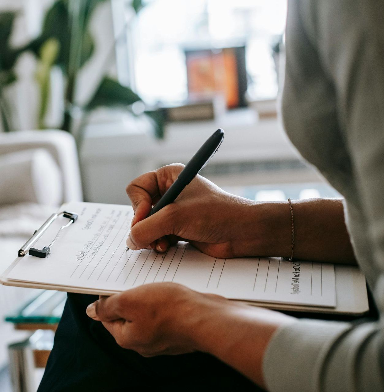 A person is writing on a clipboard with a pen