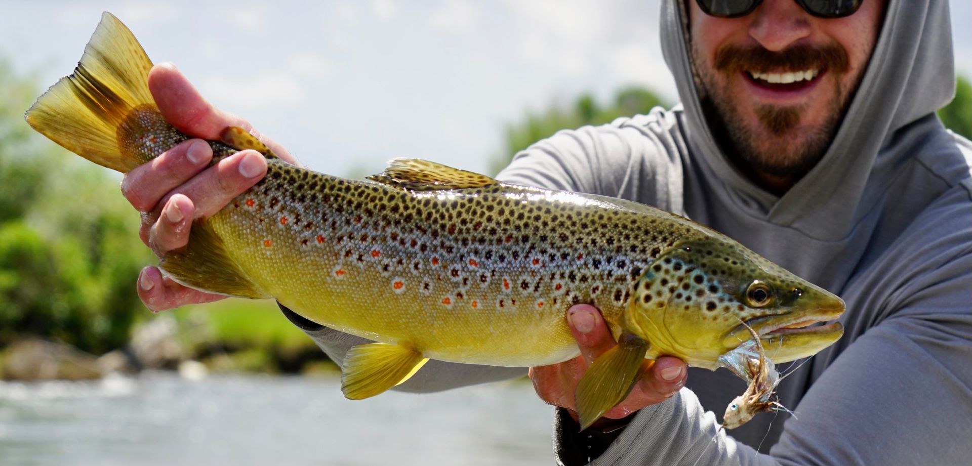 A fly angler holding a large trout on a western river