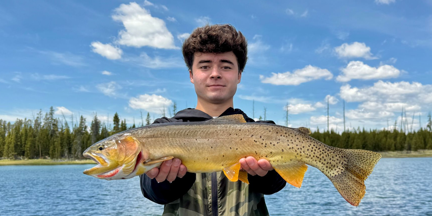 An angler cradling a large trophy trout on a western river