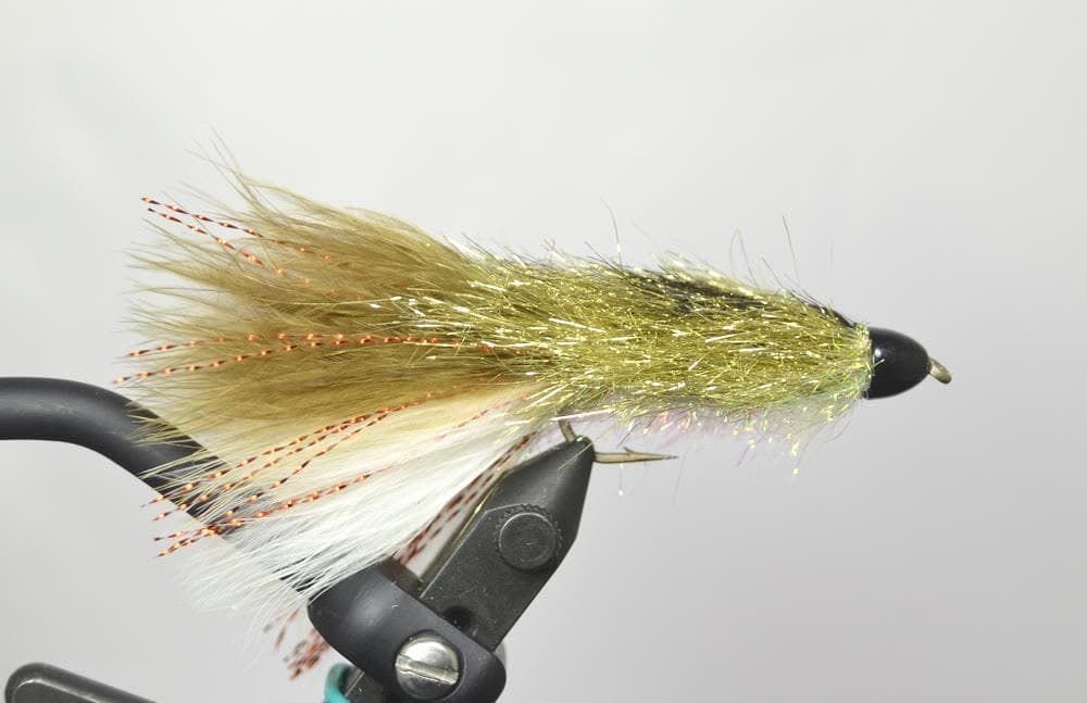 Olive and white fishing fly lure clamped in a vise against a light background