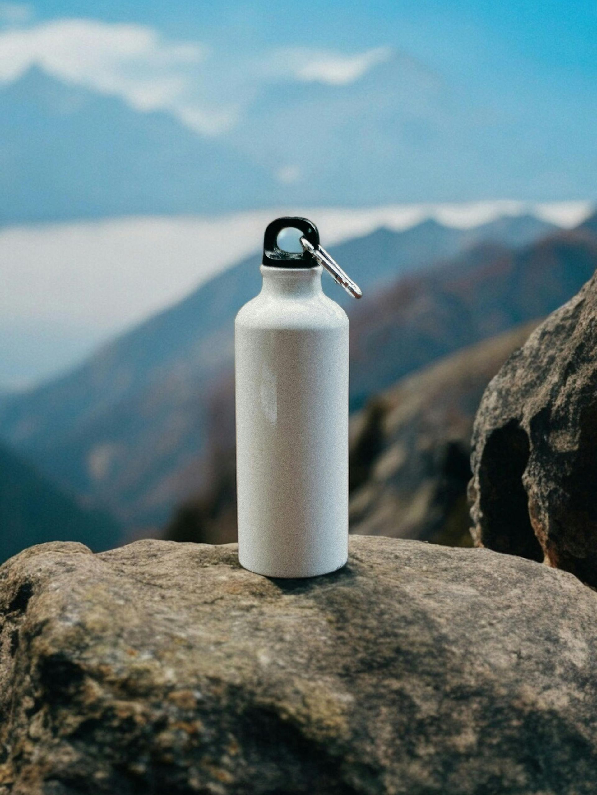 White water bottle on a rock with mountains and cloudy sky in the background