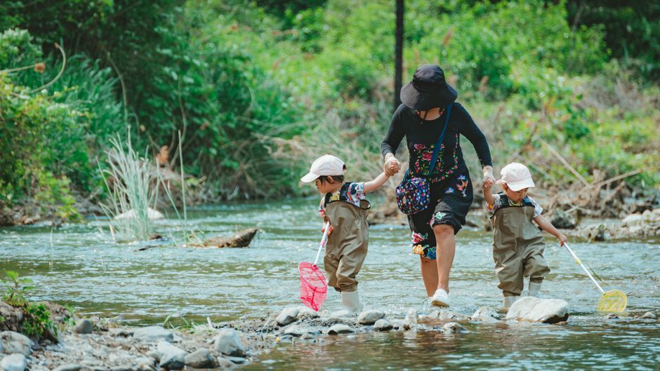 A parent and child fly fishing together on a clear Jackson Hole river