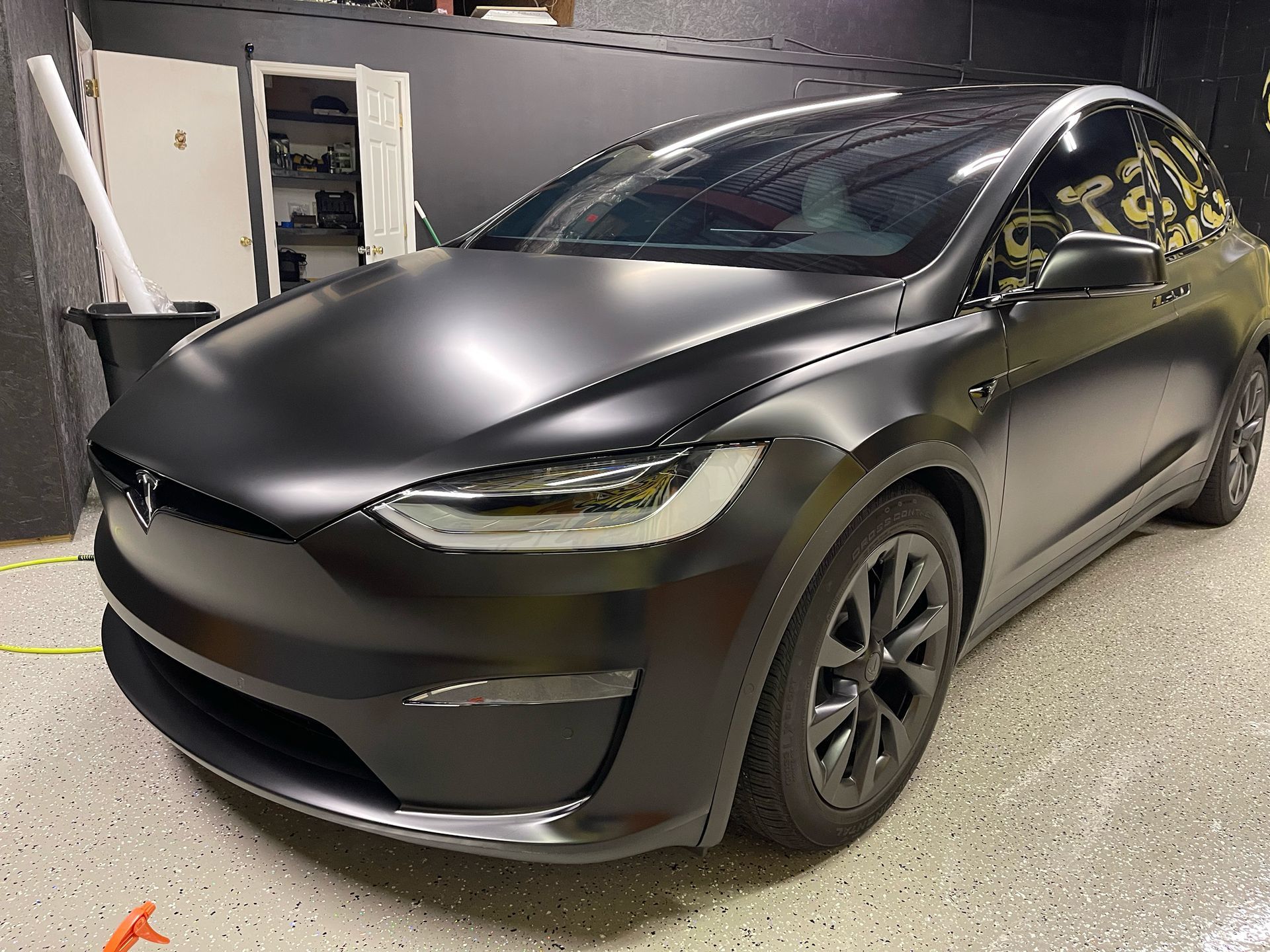 a black tesla model x is parked in a garage .